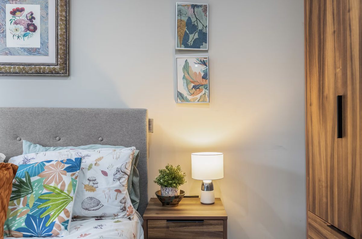 Bedside table and lamp beside a grey tufted headboard